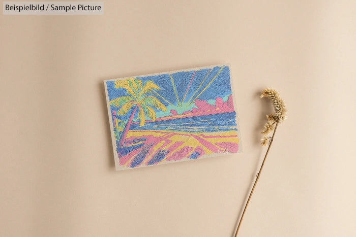Postcard with colorful beach scene and palm tree, placed on a beige surface next to a dried flower stem.