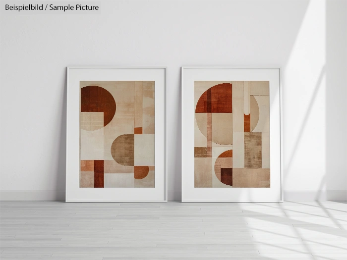 Pair of framed abstract geometric artworks with brown and beige tones leaning against a white wall on a light wood floor.