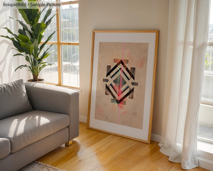 Framed geometric artwork with abstract patterns leaning against living room wall beside a couch and potted plant.