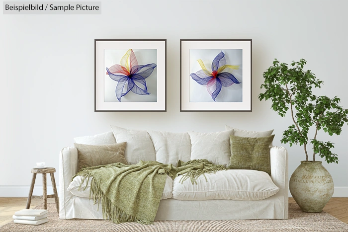 Living room with white sofa, green throw, two abstract flower paintings, and a potted plant on a textured carpet.