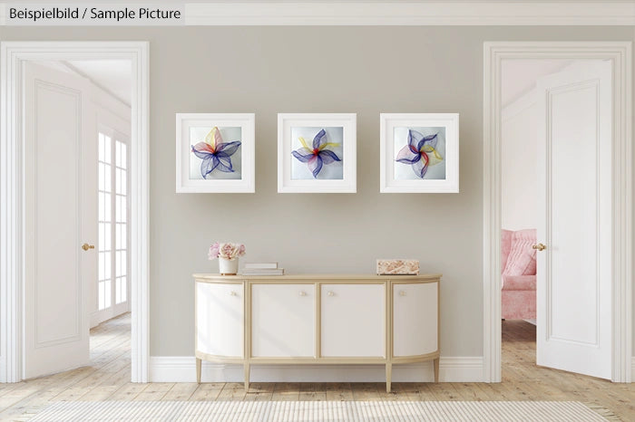 Elegant hallway with three abstract flower artworks above a modern, white sideboard.