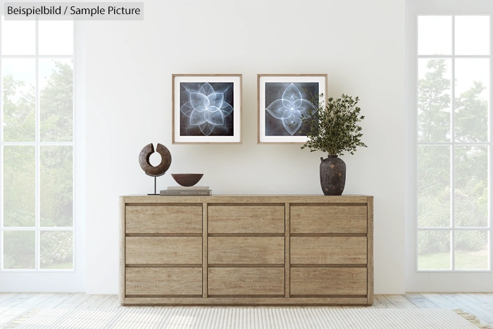 Simple room with wooden dresser, abstract art on wall, ceramic vase with greenery, and sculpture on top.
