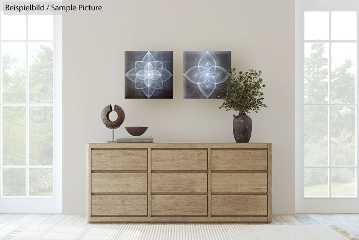 Modern living room with wooden sideboard, abstract art, round sculpture, vase with branches, and large windows.
