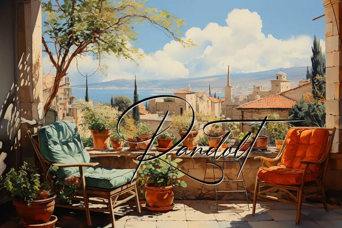 Sunny terrace with two chairs, plants, and a scenic view of a Mediterranean town and sea in the background.