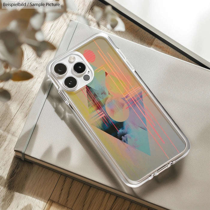 Smartphone with abstract geometric design case resting on a notebook, photographed on a wooden surface.