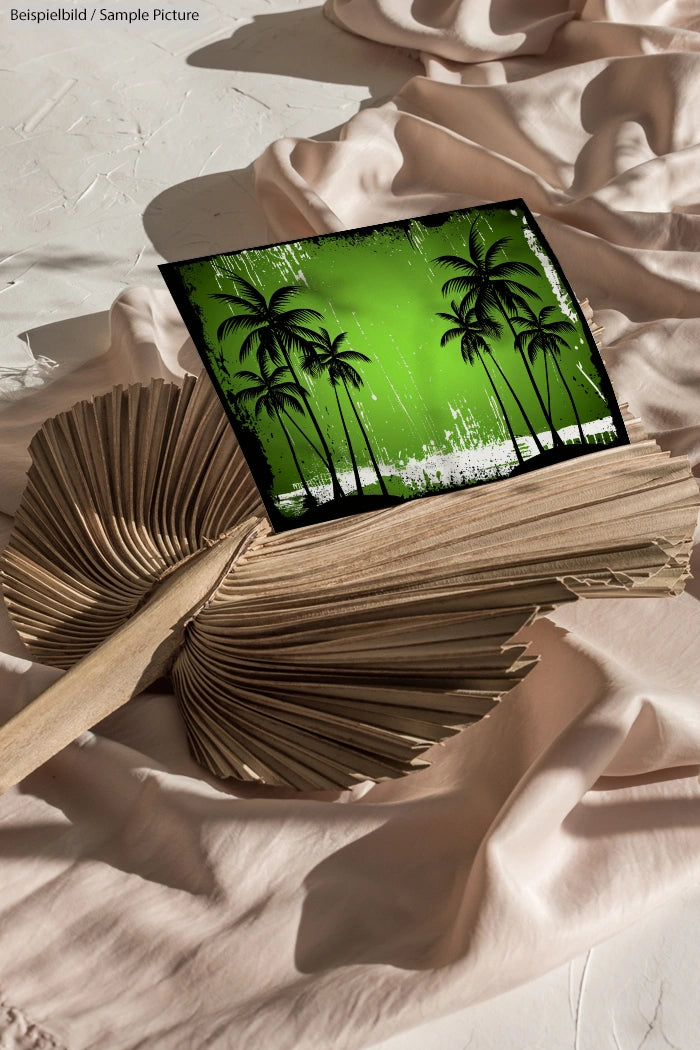 Photo placed on palm leaf, featuring green tropical scene with silhouette of palm trees against white fabric background.