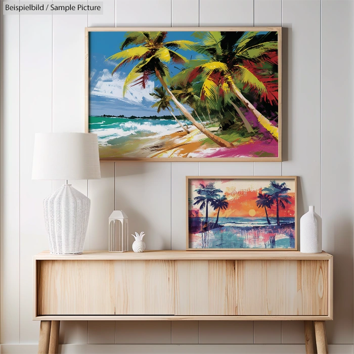 Room interior with two framed tropical beach paintings, wooden console, white lamp, and decorative white vase.