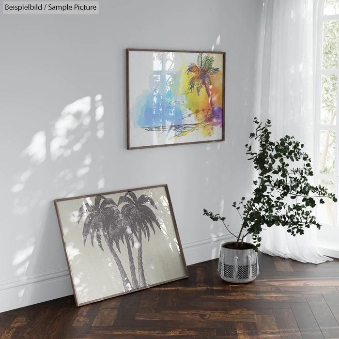 Sunny room with palm tree artworks; one colorful on wall, another black and white leaning on floor near potted plant.
