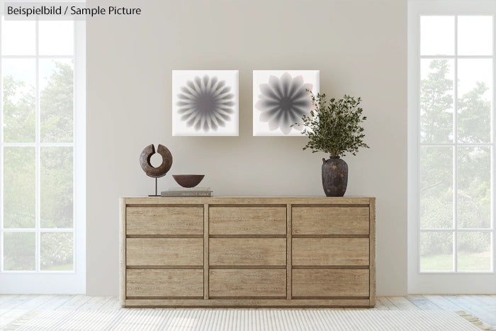 Minimalist living room with wooden dresser, abstract wall art, and potted plant by large windows.