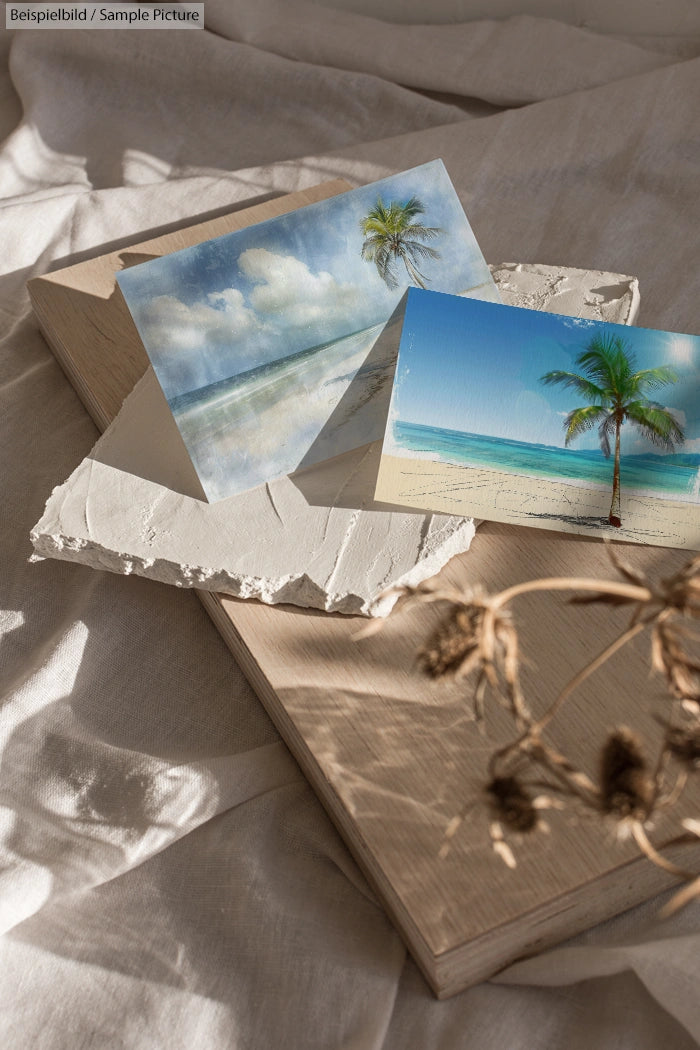 Two beach postcards on a textured surface with dried flowers and soft lighting.