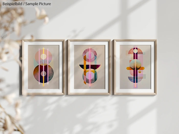 Three framed abstract geometric prints on a wall, featuring colorful circular and linear designs in soft, warm tones.