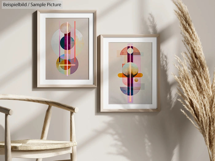 Two framed abstract prints on beige wall with wooden chair and pampas grass in foreground.