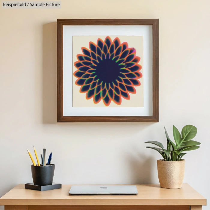 Framed artwork of a geometric flower design above a desk with a closed laptop, pencil holder, and a potted plant.