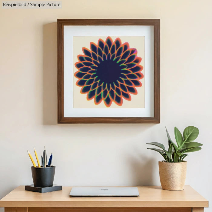Framed artwork of a geometric flower design above a desk with a closed laptop, pencil holder, and a potted plant.