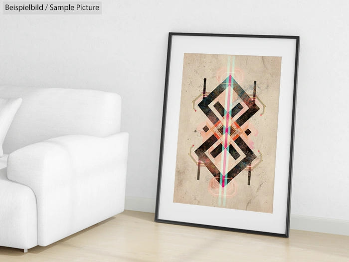 Framed abstract geometric art print with bold shapes, leaning against a white sofa in a minimalist room.