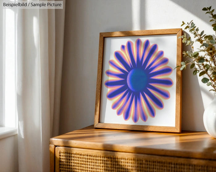 Framed abstract flower print with vibrant blue and orange petals, displayed on a wooden sideboard near a sunlit window.